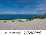 The Carrick-a-Rede rope bridge, Northern Ireland seaside walk along the seafront, with stunning sea views, a blue sky, a scenic walking trail, and sight-seeing benches