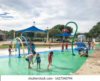 CARROLLTON, TX, US-JUNE 4, 2019:Diverse Kids Enjoy Water Splash Pad Or Spray Ground At Public Park Near Dallas. Water Fountain Activities For Children And Parent During Summer Time, Overcast Weather