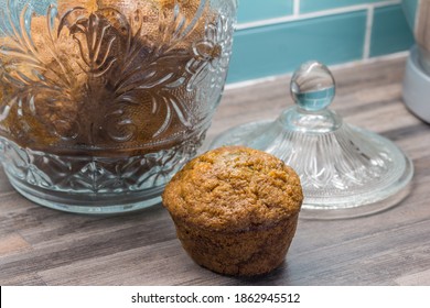 Carrot, Apple, Cinnamon, Pumpkin Seed Muffin On Kitchen Countertop Next To Glass Jar With Muffins