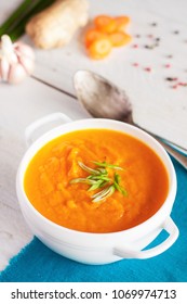 Carrot ginger cream soup with fresh ingredients on white rustic board - Shutterstock ID 1069974713