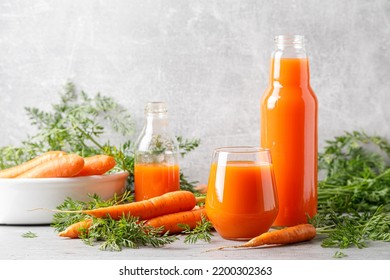 Carrot juice in a glass and bottle and fresh carrots with leaves - Shutterstock ID 2200302363