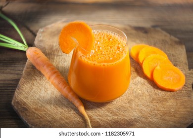 Carrot juice in glass on wooden table