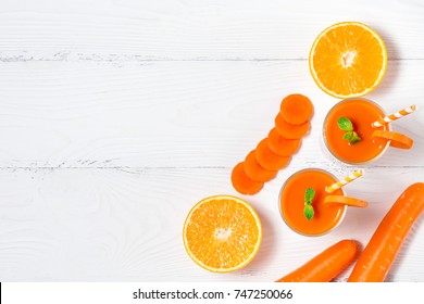 Carrot and orange smoothie with ingredients on white background with copyspace. Top View