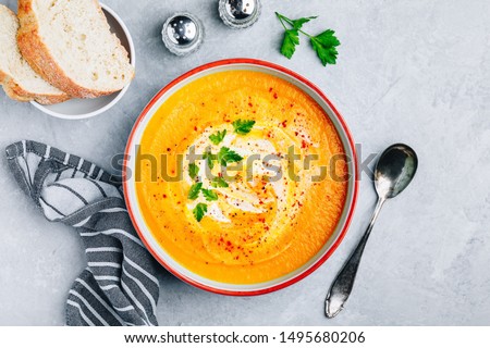 Carrot and pumpkin cream soup with parsley on gray stone background. Top view, copy space