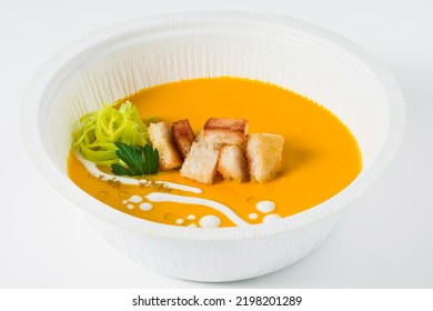 Carrot Puree Soup With Croutons And Leeks In A Plastic Takeout Container