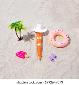 A Carrot Sunbathing On A Sandy Beach In A Bathing Suit With Beach Props. Summer With A Copper Complexion.