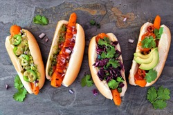 Carrot Vegan Hot Dogs With Assorted Toppings. Above View Scene On A Dark Slate Background. Plant Based Meatless Meal Concept.