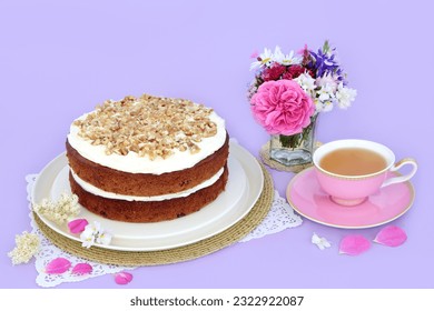 Carrot and walnut cake with cup of tea and summer flowers on purple background. Homemade delicious food concept for afternoon tea or birthday party. - Powered by Shutterstock