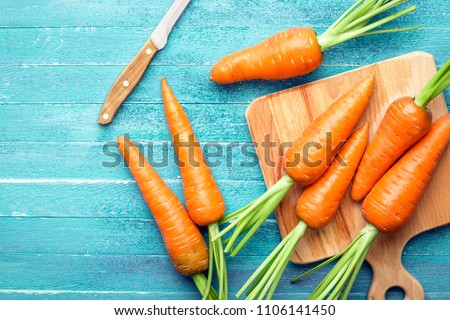 carrots on a blue wooden background, cutting board and knife, fresh vegetables, carotene