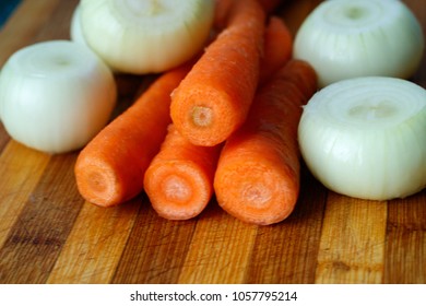 carrots and onion cleaned but not cut on a cutting board on a wooden background, fresh vegetables for cooking