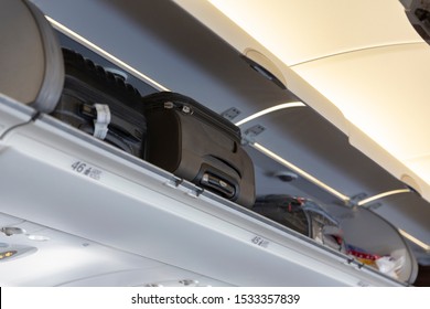 Carry On Bag On Top Shelf Of Plane. Hand Luggage Compartment With Suitcases In Airplane. Travel Concept With Copy Space Text Area. 