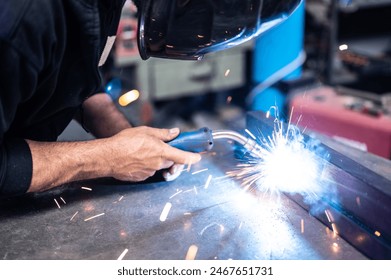 Carrying out a weld: the man in the welding mask positioned himself with the welding machine on the welding point: sparks,glow and smoke.Conceptual image of work,metalworking,craftsmanship. Copyspace. - Powered by Shutterstock