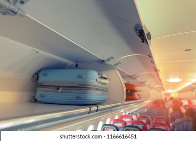 Carry-on luggage on the top shelf over head on airplane, passenger put bag cabin compartment air craft business class,vintage color,copy space