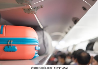 Carry-on luggage on the top shelf  over head on airplane, passenger put bag cabin compartment air craft  business class,vintage color,copy space