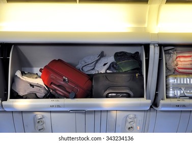 Carry-on luggage in overhead storage compartment on commercial airplane.