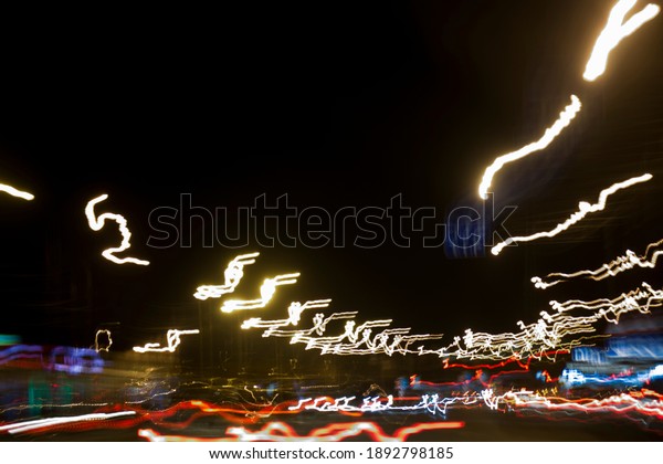 Cars bright white and yellow night lights on road\
highway band on long exposure. Fast movement light glowing lights\
in dark city