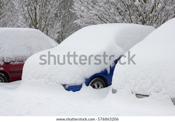 Cars buried in snow in\
parking lot, snowy car park at the city after a heavy snow fall,\
winter calamity