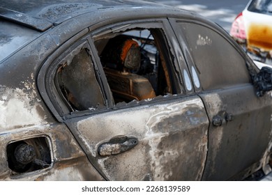Cars burned down in the middle of the street. Windows shattered from the explosion. Burned out new car in the city street, vandalism, mafia. Setting fire to cars by vandalism and damage to property