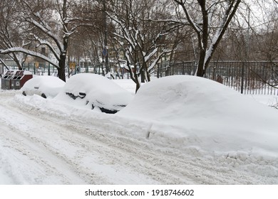 Cars covered with snow after a hard blizzard on the roadside of a Moscow street in snowy winter