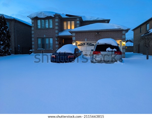Cars covered with snow on a driveway in\
residential area and unable to drive out during heavy snowstorm.\
Snow storm, blizzard, driving conditions, extreme weather warning\
and alert concept.