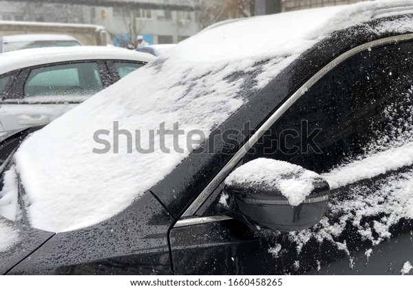 cars covered snow in parking\
under winter heavy snowfall, bad weather condition for\
trasportation