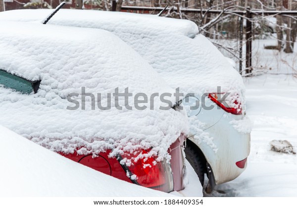 Cars covered with a\
thick layer of snow in a snow-covered street Parking lot in a\
residential area of the\
city