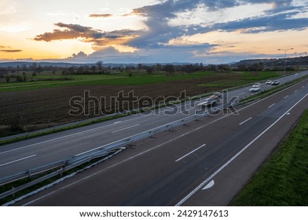 Cars drive at high speed on the highway through the rural landscape. Fast blurred highway driving. A scene of speeding on the highway.
