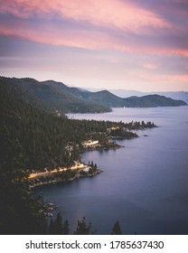 Cars Driving Along The Shore Of Lake Tahoe At Dusk.