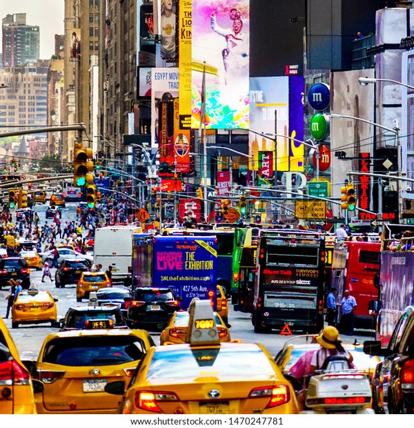 Cars driving\
through Times Square in Manhattan with billboards. Manhattan, New\
York, USA - June 20, 2015