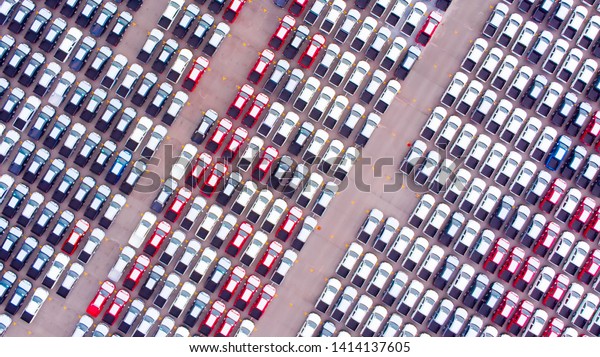 Cars export terminal in export and import business\
and logistics. Shipping cargo to harbor. Aerial view of a large\
number of  new cars lined up outside an automobile factory ready to\
ship over sea.