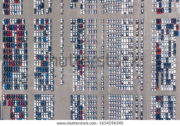 Cars export terminal in export and import business\
and logistics. Shipping cargo to harbor. Aerial view of a large\
number of new cars lined up outside an automobile factory ready to\
ship over sea.
