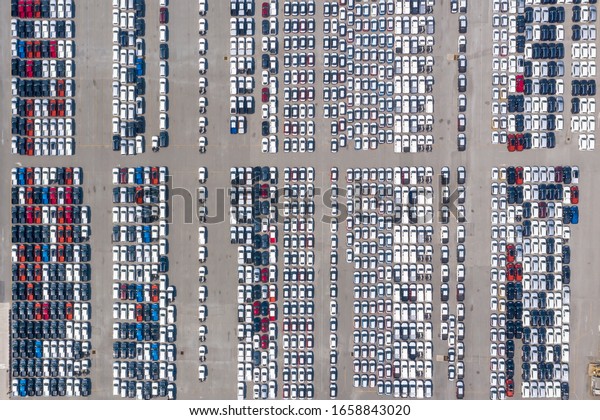 Cars export terminal in export and import business\
and logistics. Shipping cargo to harbor. Aerial view of a large\
number of new cars lined up outside an automobile factory ready to\
ship over sea.