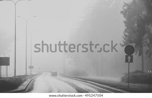Cars in the fog. Bad weather and\
dangerous automobile traffic on the road. black and\
white
