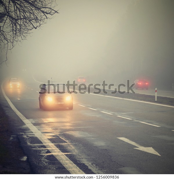 Cars in the fog.\
Bad winter weather and dangerous automobile traffic on the road.\
Light vehicles in foggy\
day.