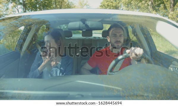 Car's interior. Young Caucasian couple fighting.
Jealousy. Problems in relationship. Summertime. Attractive woman
and boyfriend. Automobile, concept, trip, vacation, safety,
journey, way, metal