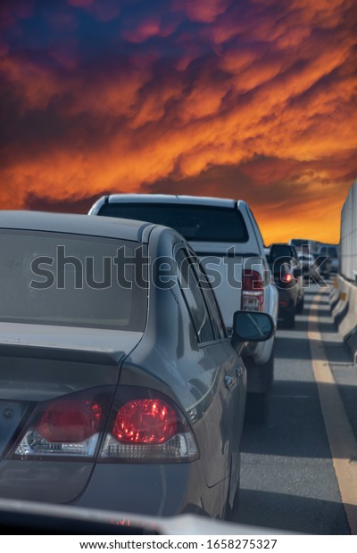 Cars jam on a tollway during rush hours in a morning or\
evening usually seen in big cities. View from a front car seat of a\
waiting car on an express way with a nice evening clouds in a\
background. 