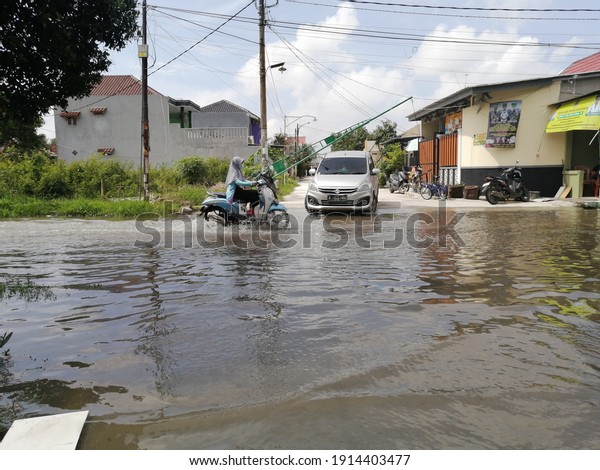 Cars and motorbikes\
are passing through the flooded road. February 8, 2021. Bekasi,\
West Java, Indonesia