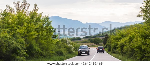 Cars move along a winding highway in the\
highlands in summer.