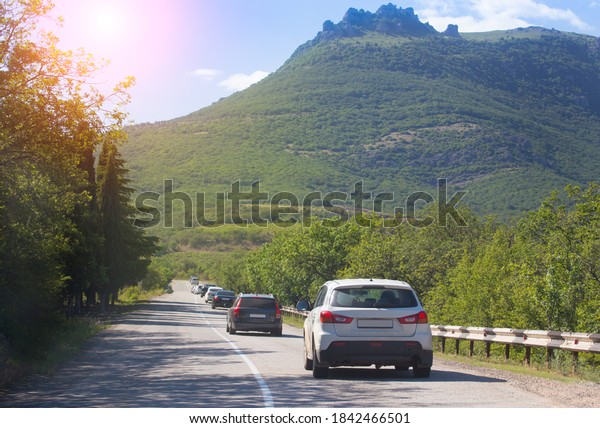 Cars\
move along a winding mountain road on a summer\
day