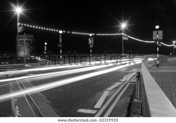 Cars moving past a\
pedestrian crossing, creating lines of light at Shannon Bridge\
Limerick city Ireland.