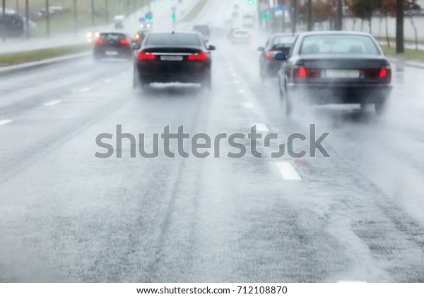 cars moving in wet road with
water spraying from the wheels. blurred view through
windshield.