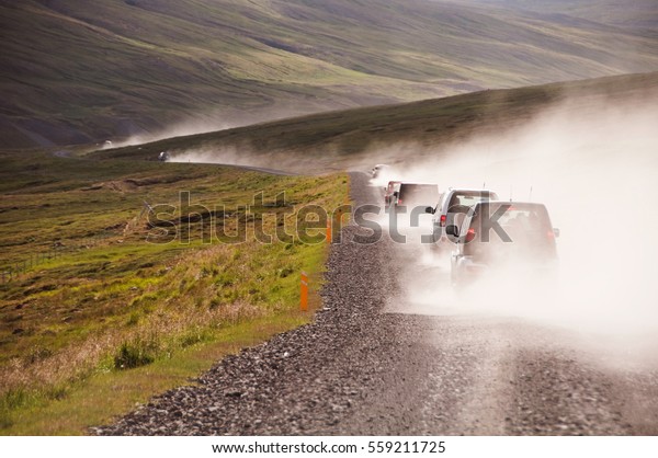 Cars on dusty road in\
Iceland