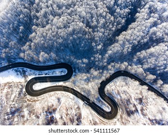 Cars on road in winter with snow covered trees aerial view