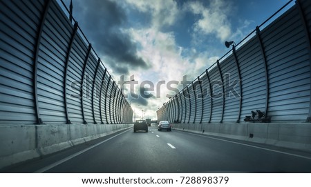 Cars on the sound-absorbing tunnel at the asphalt road. Metal structure with plastic parts. Modern technology in the Moscow Russia