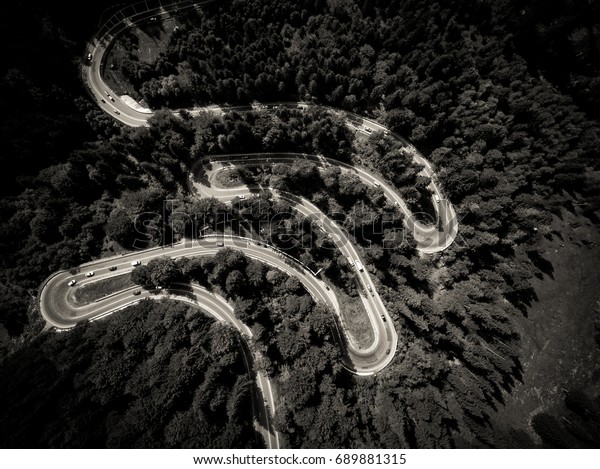 Cars on\
winding road trough the forest aerial\
view