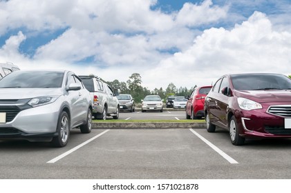 Cars Parked In Asphalt Parking Lot. Trees, White Cloud Blue Sky Background, Empty Space For Car Parking. Outdoor Parking Lot With Green Environment. Nature Travel Transportation Technology Concept
