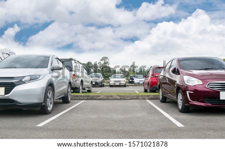 Cars parked in asphalt parking lot. Trees, white cloud blue sky background, empty space for car parking. Outdoor parking lot with green environment. nature travel transportation technology concept