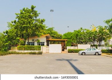 Cars Parked At Large Parking Lots There Is A Shadow Of A Street Light Post The Back Is A Single-story House. Covered With Trees