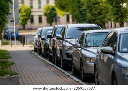 Cars parked next to a paved side walk in afternoon