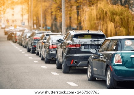 Cars parked at roadside in residential area, parking zone. Parking problems not enough free space. Crowded public parking lot on narrow street. Rows of cars parked on roadside